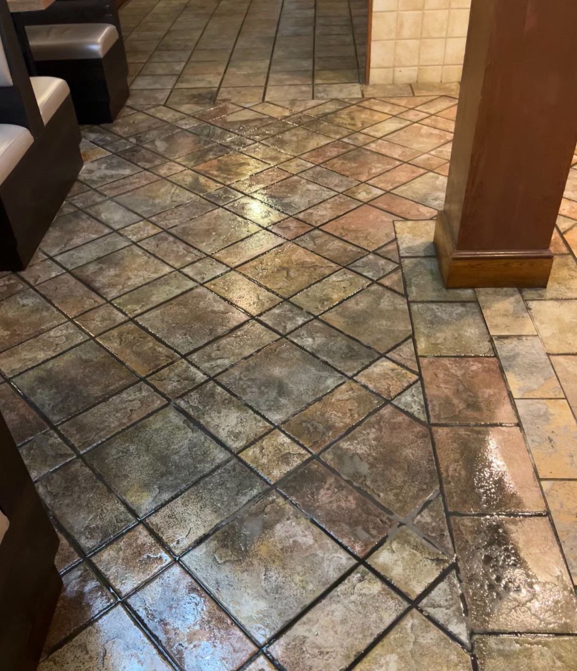 Brown and tan tiled floor in a restaurant with a diamond pattern, near a booth and column.