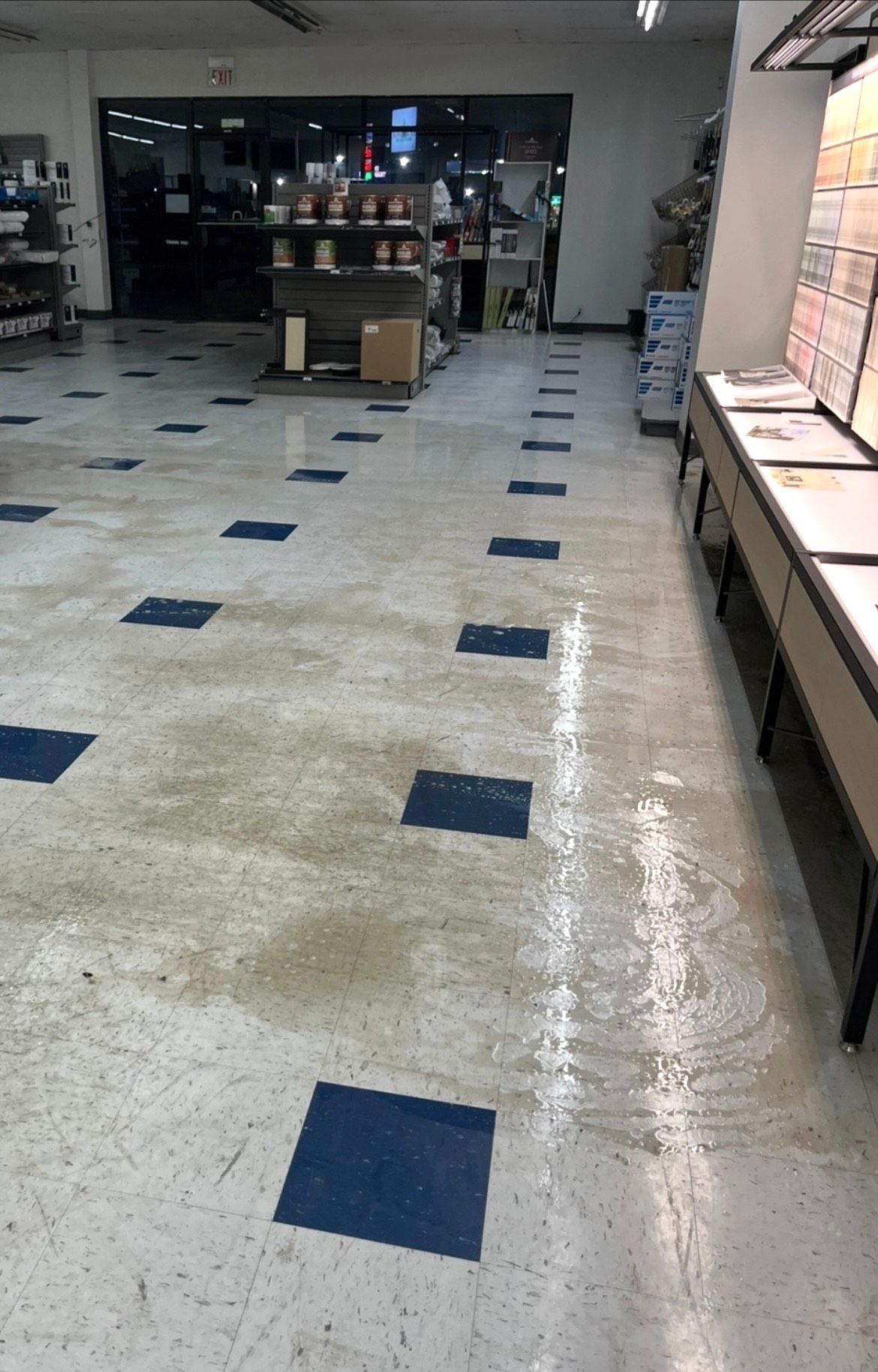 A flooded store floor with a row of displays on the right and a dark entrance in the background.