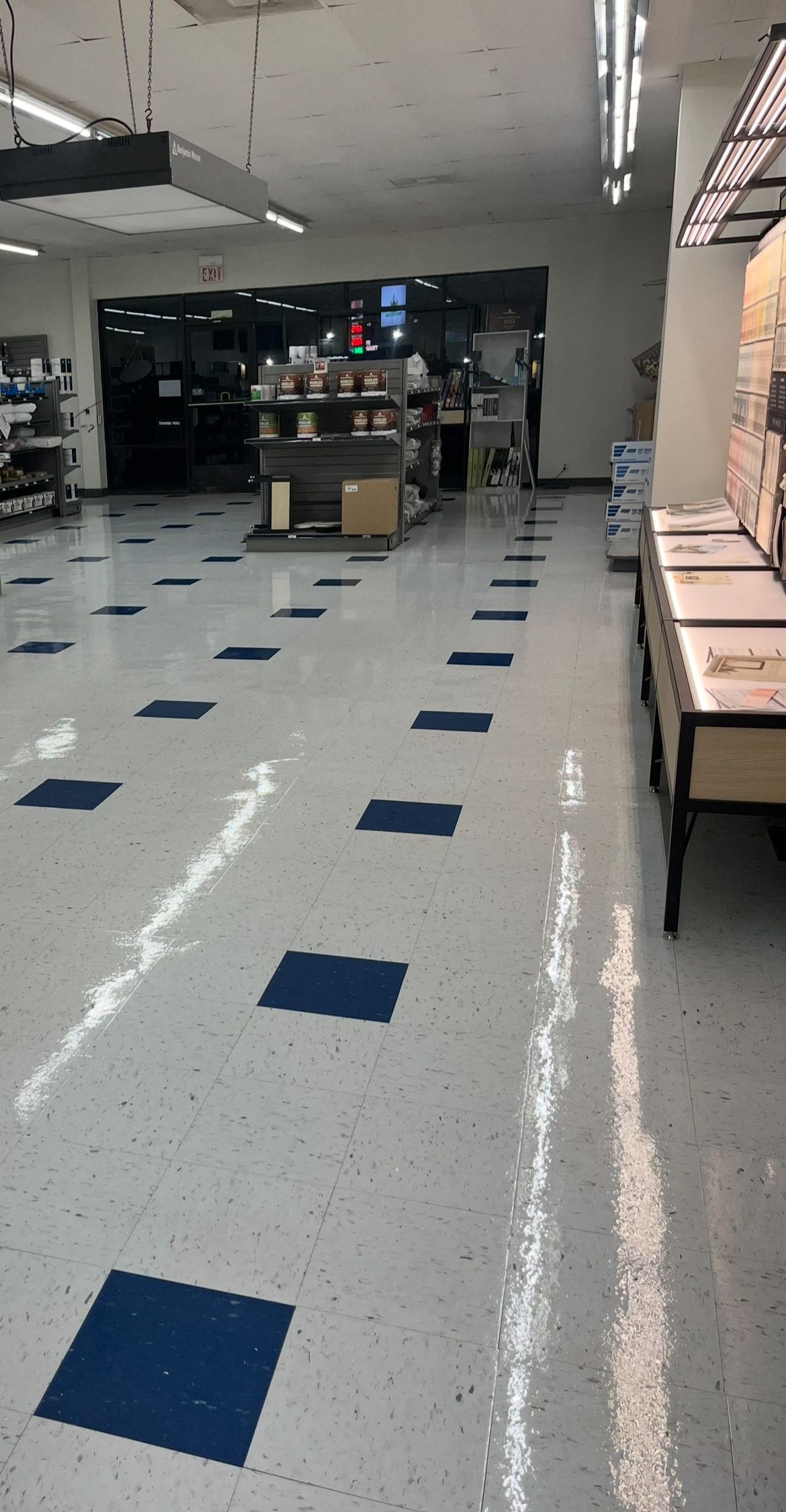 Empty grocery store aisle with blue and white floor tiles.