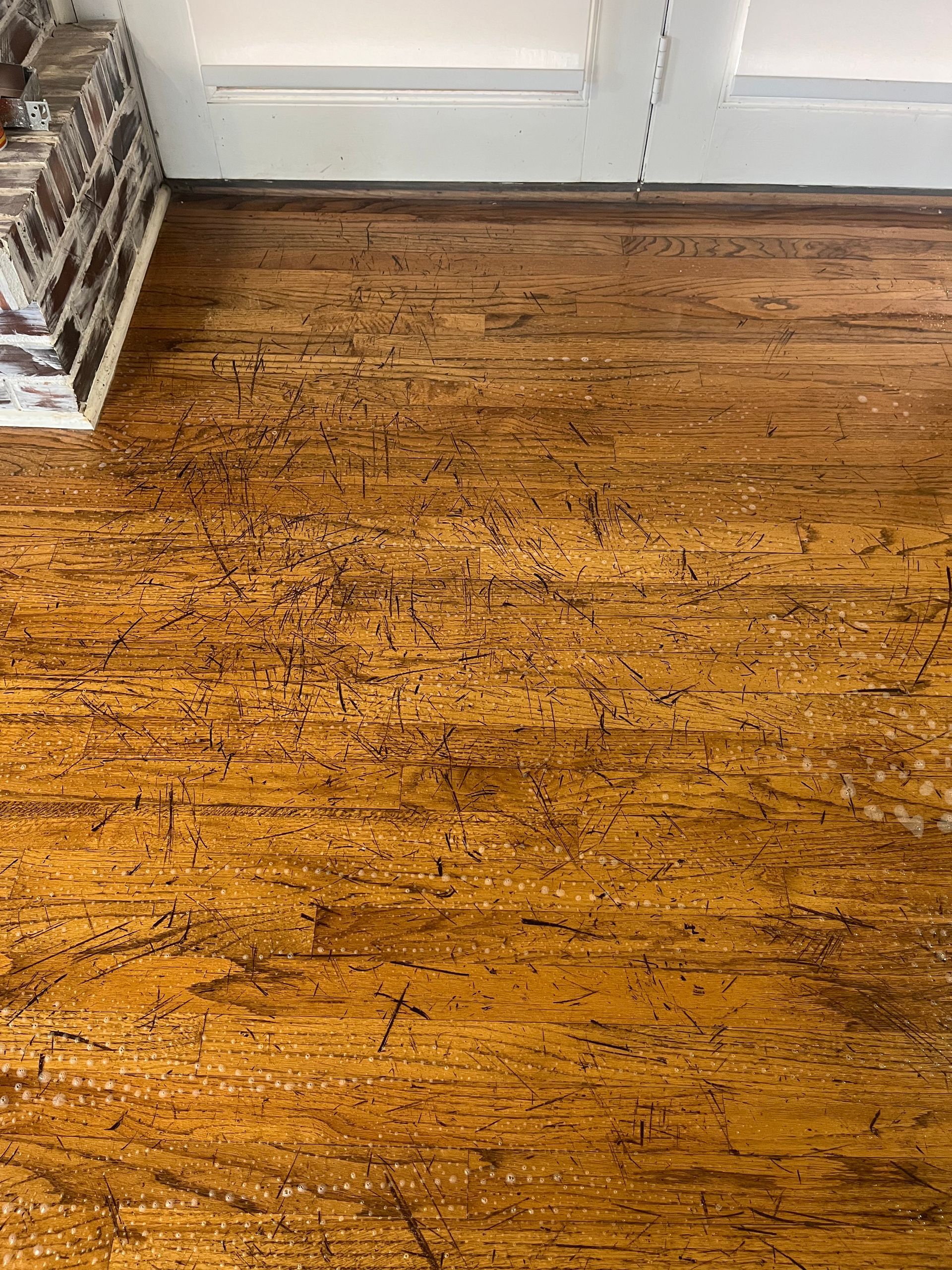 Close-up view of a wood floor with distressed finish, some light-colored flecks present.