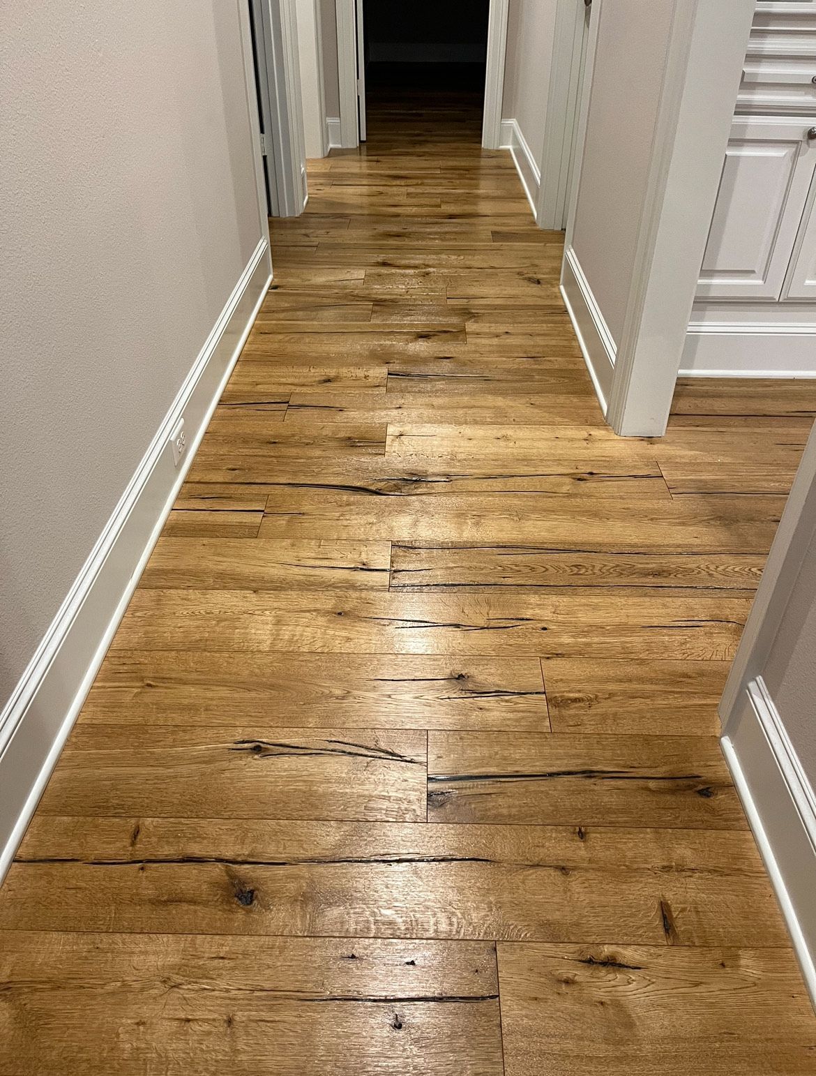 Wooden floor hallway with gray walls and white trim.