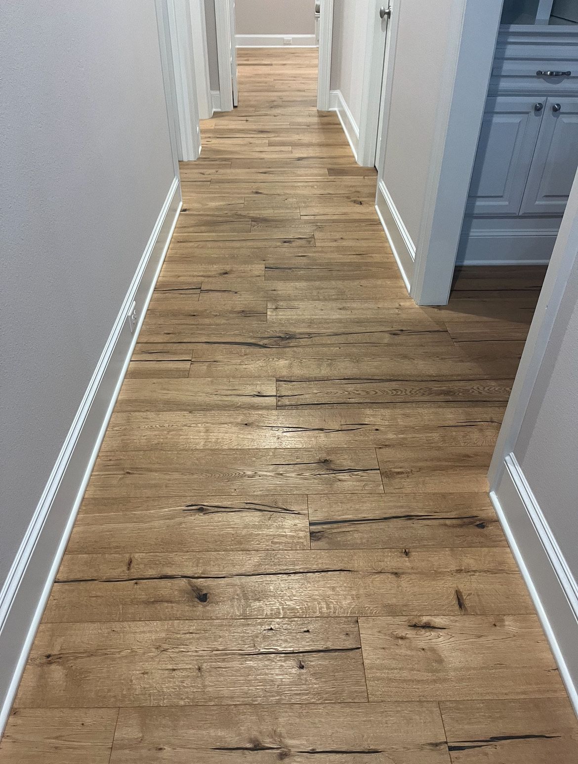 Wooden hallway with weathered planks, white trim, and gray walls.