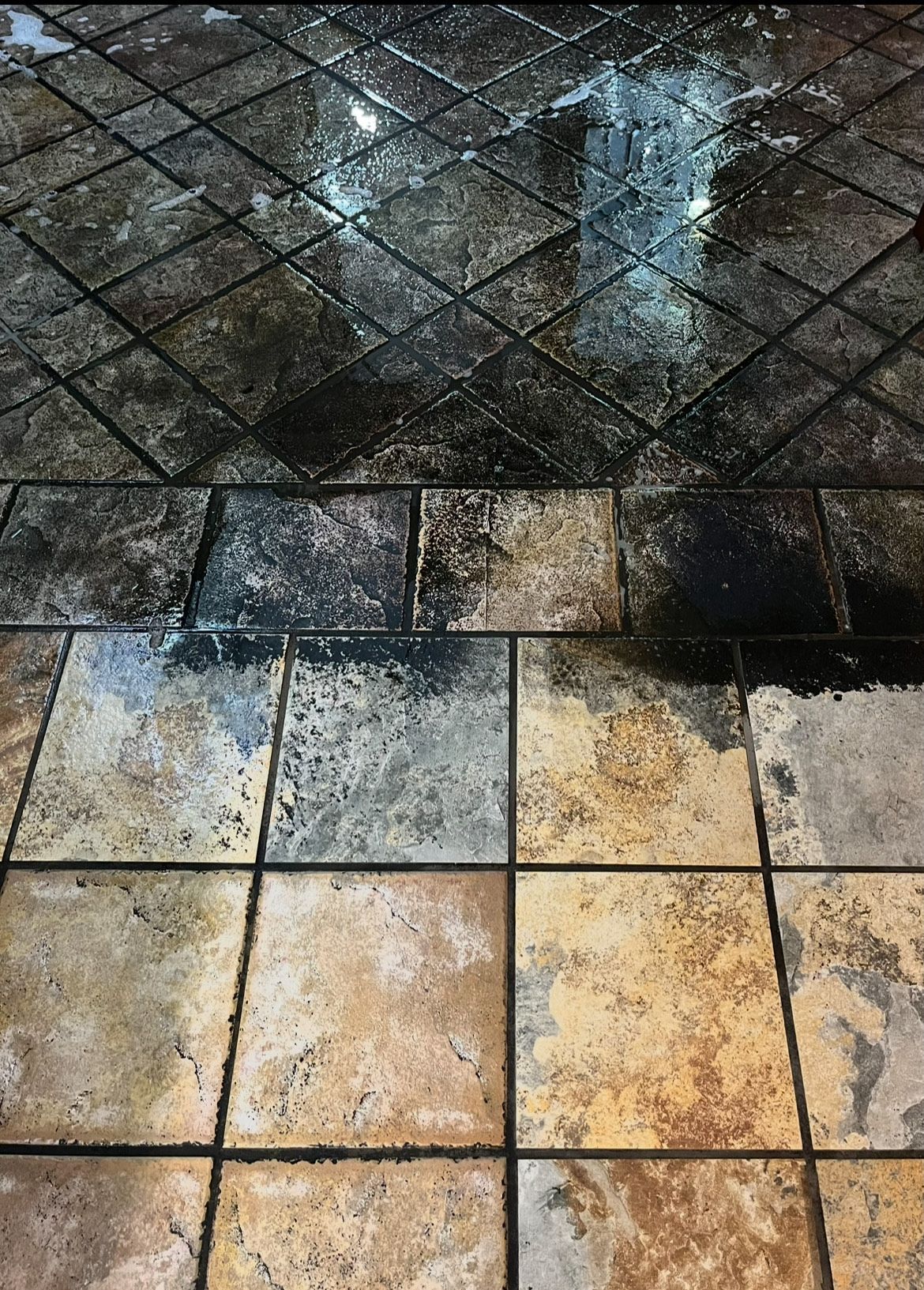 Wet, patterned tile floor with darker cleaned areas.