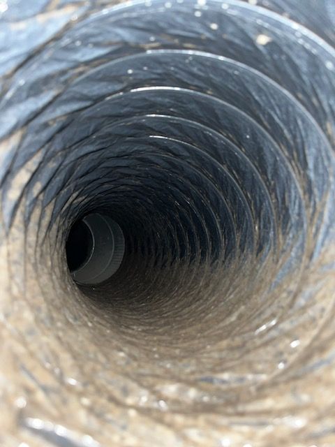 Looking down the interior of a dirty, flexible air duct.