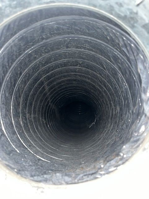 Inside view of a circular metal duct, spiraling inward and appearing dark.