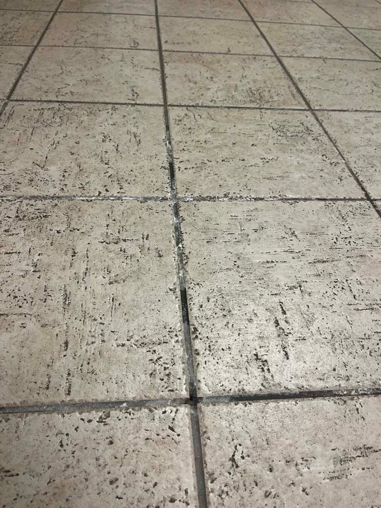 Beige floor tiles with dark grout lines.