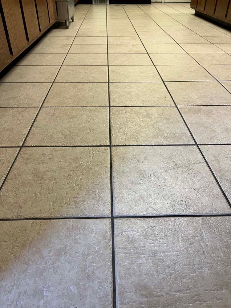 Tan tile floor with dark grout lines, viewed from a low angle.