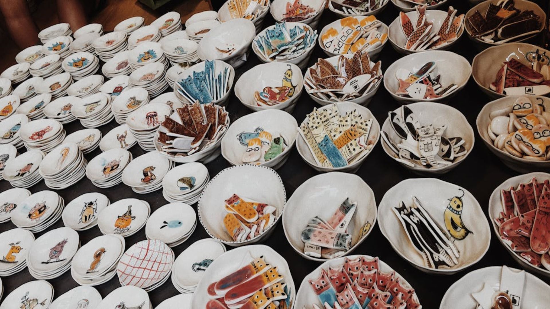 Cuencos de cerámica pintados a mano con diversos diseños coloridos en exhibición en un mercado.