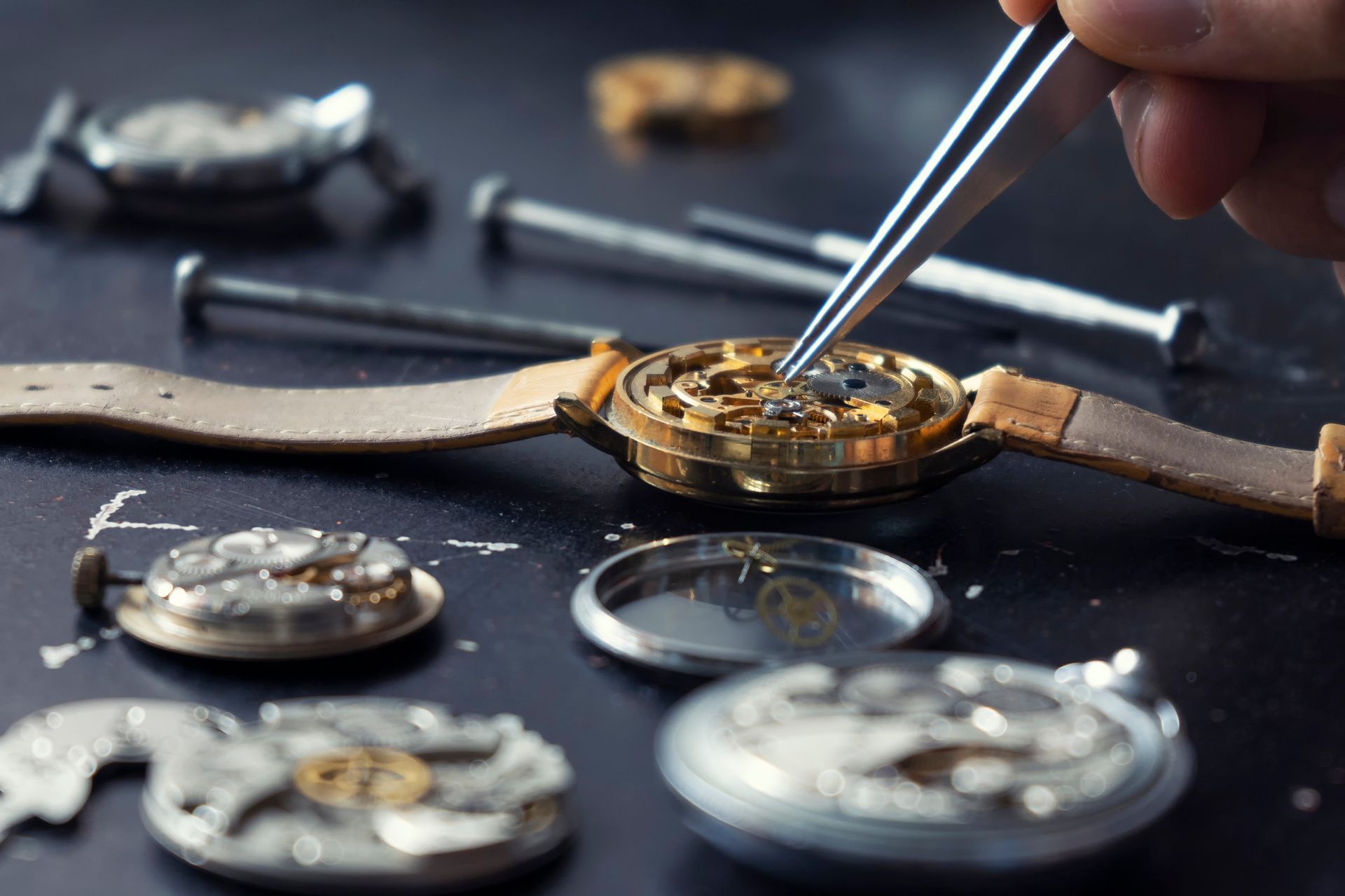 Close-up of watch repair: Watchmaker uses tweezers on intricate gears, parts scattered on a dark surface.