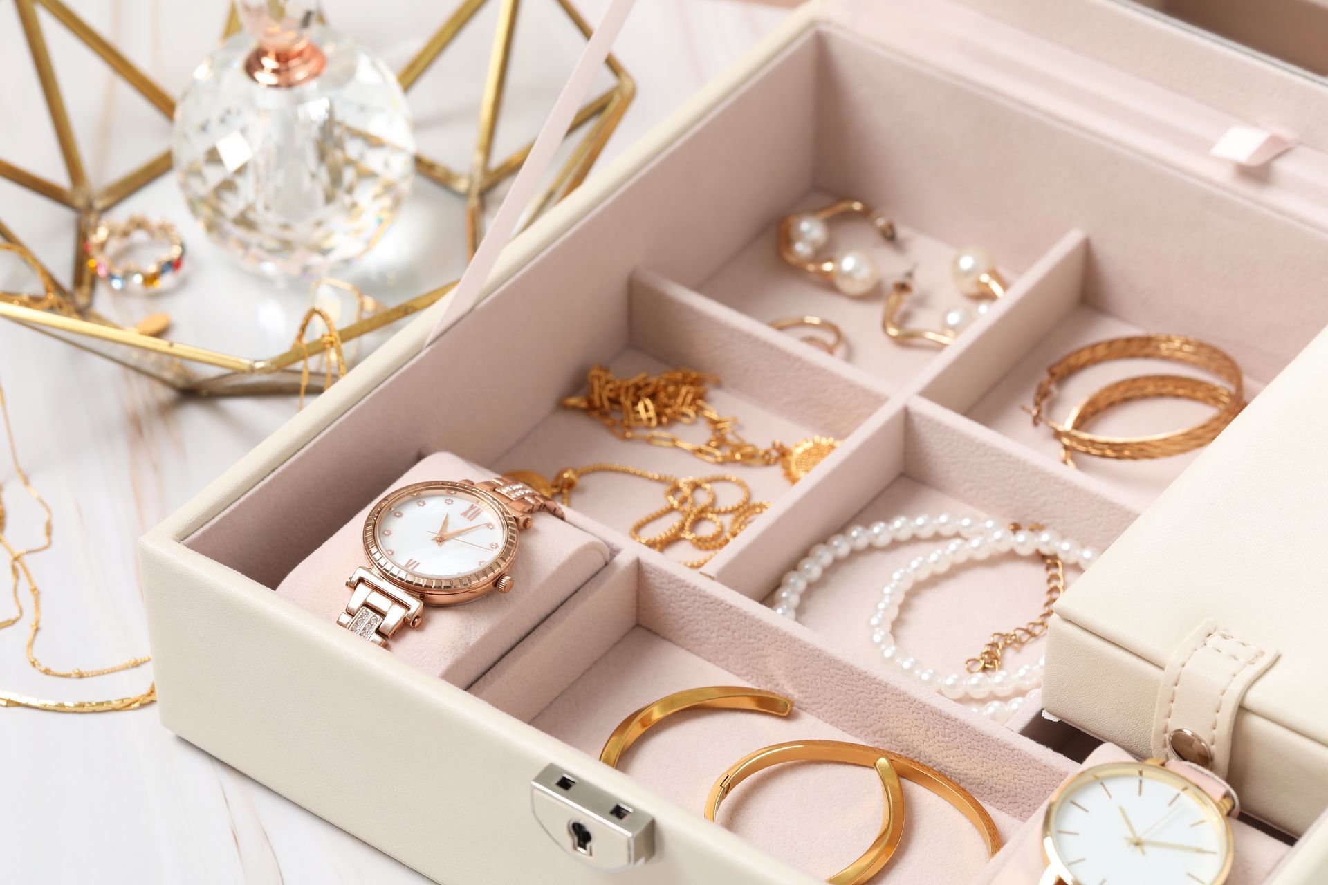 Jewelry box open, displaying gold and pearl jewelry, watches, and accessories.