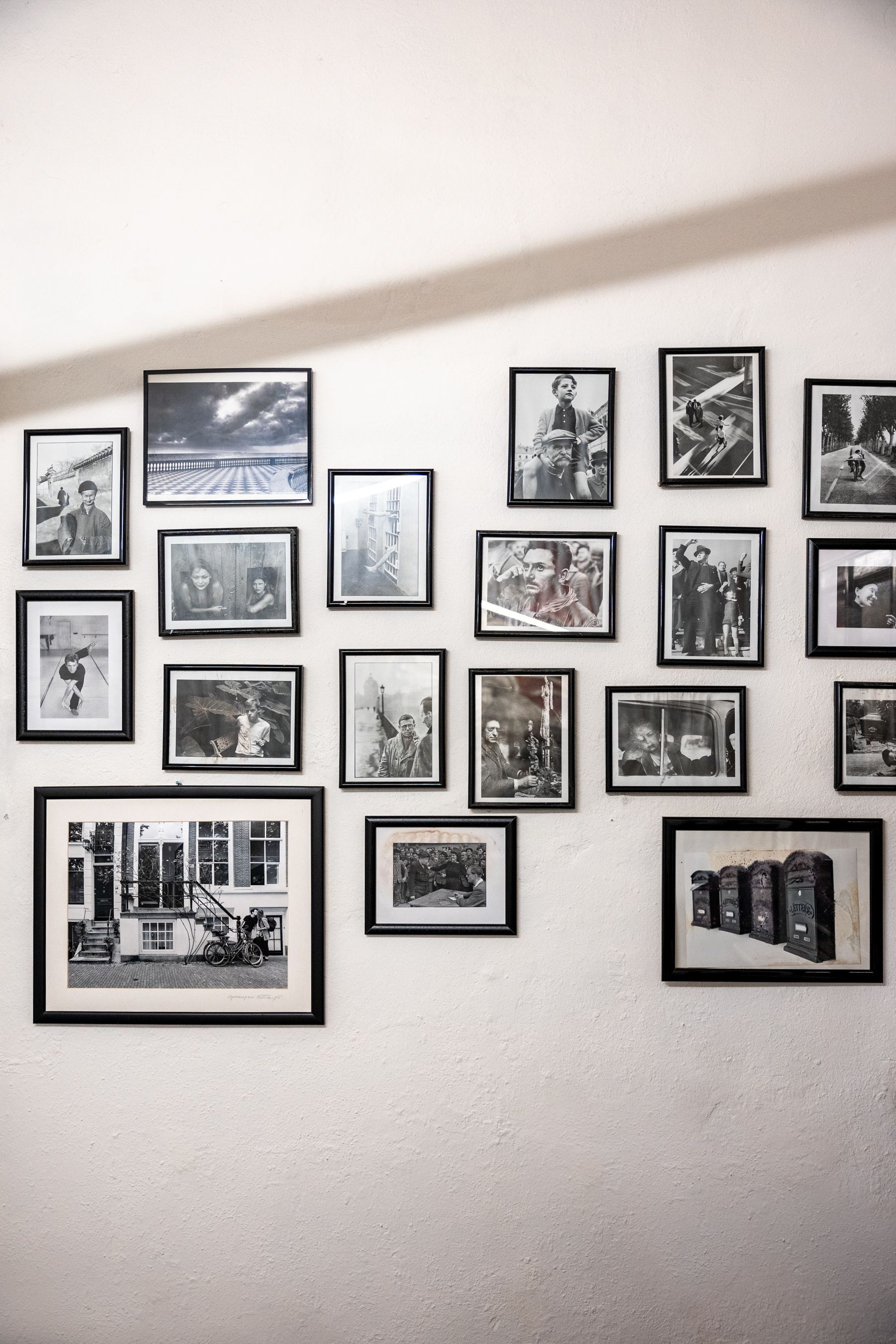 Parete con una galleria di varie foto e stampe incorniciate, in bianco e nero e a colori.