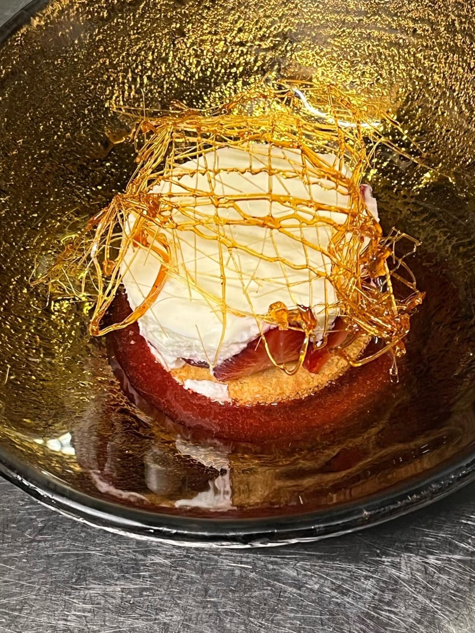 Dessert in una ciotola scura con glassa al caramello e ripieno di crema bianca.