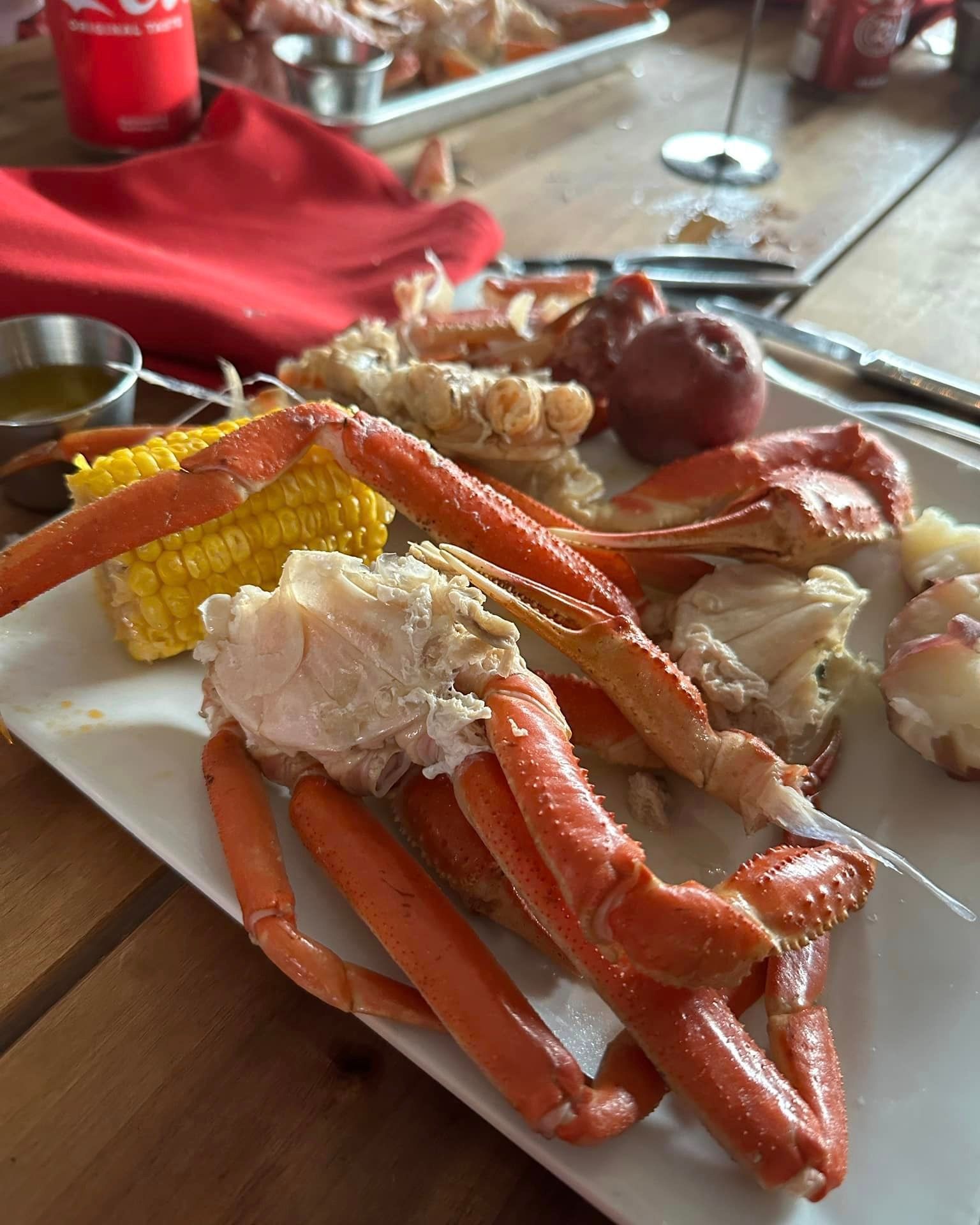 A plate of crab legs and corn on the cob on a table.