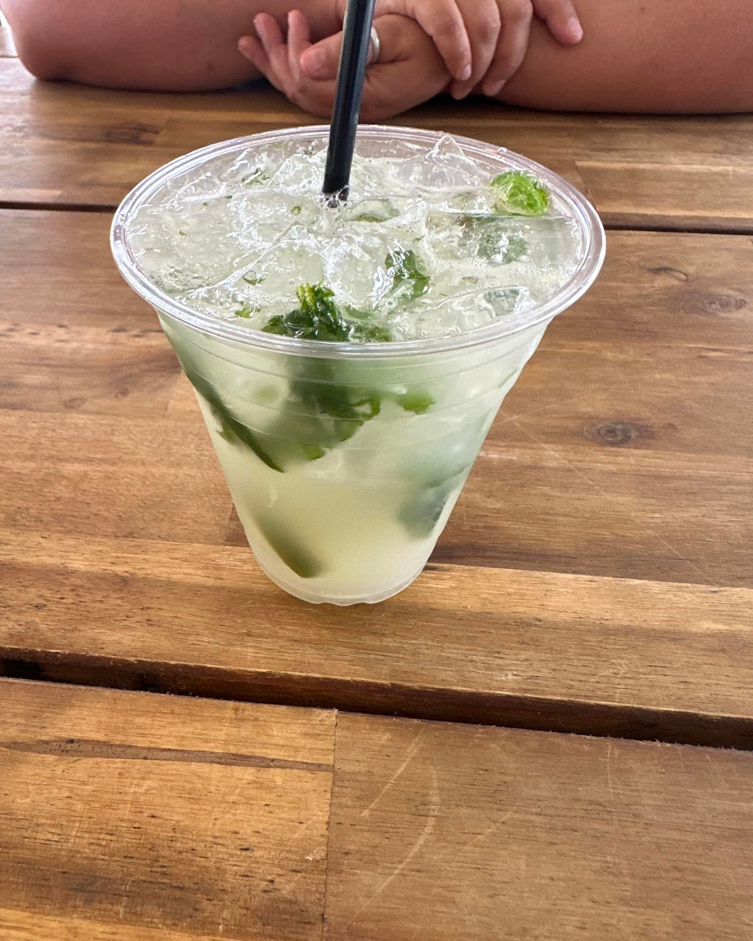 A drink in a plastic cup with a straw on a wooden table.
