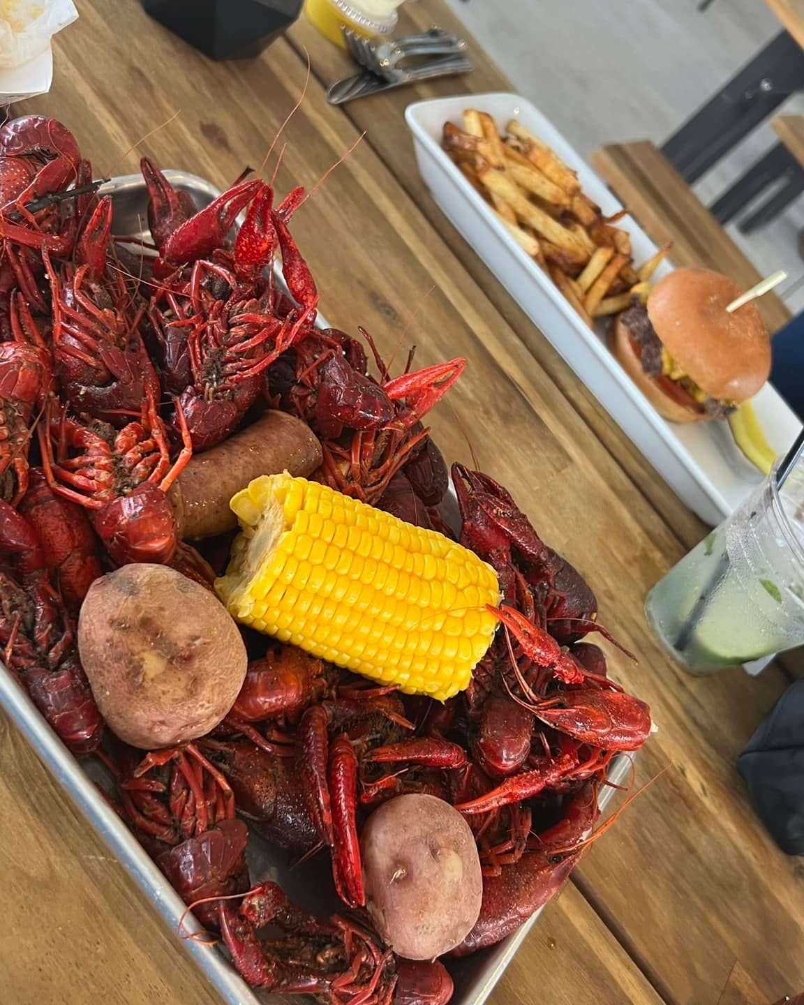 A tray of crawfish with corn on the cob and potatoes on a wooden table.
