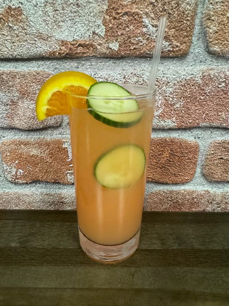 A red-colored drink with shrimp and fruits on top of it