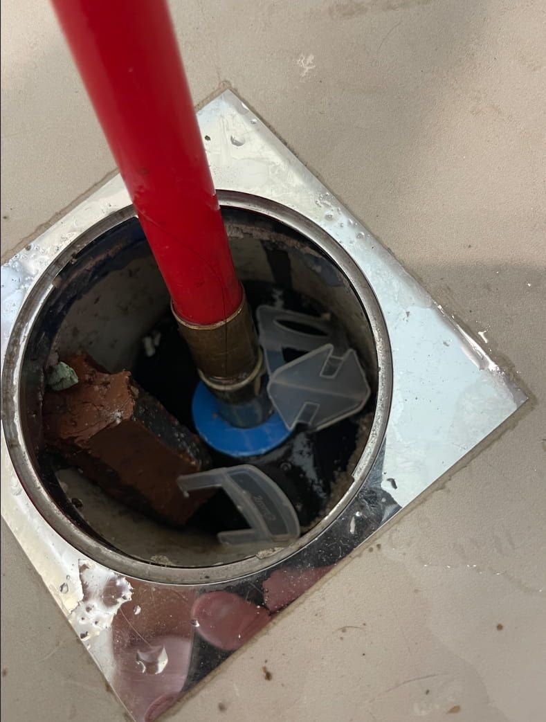 A Red Stick Is Sticking Out Of A Hole In A Drain — Panorama Plumbing In Dubbo, NSW