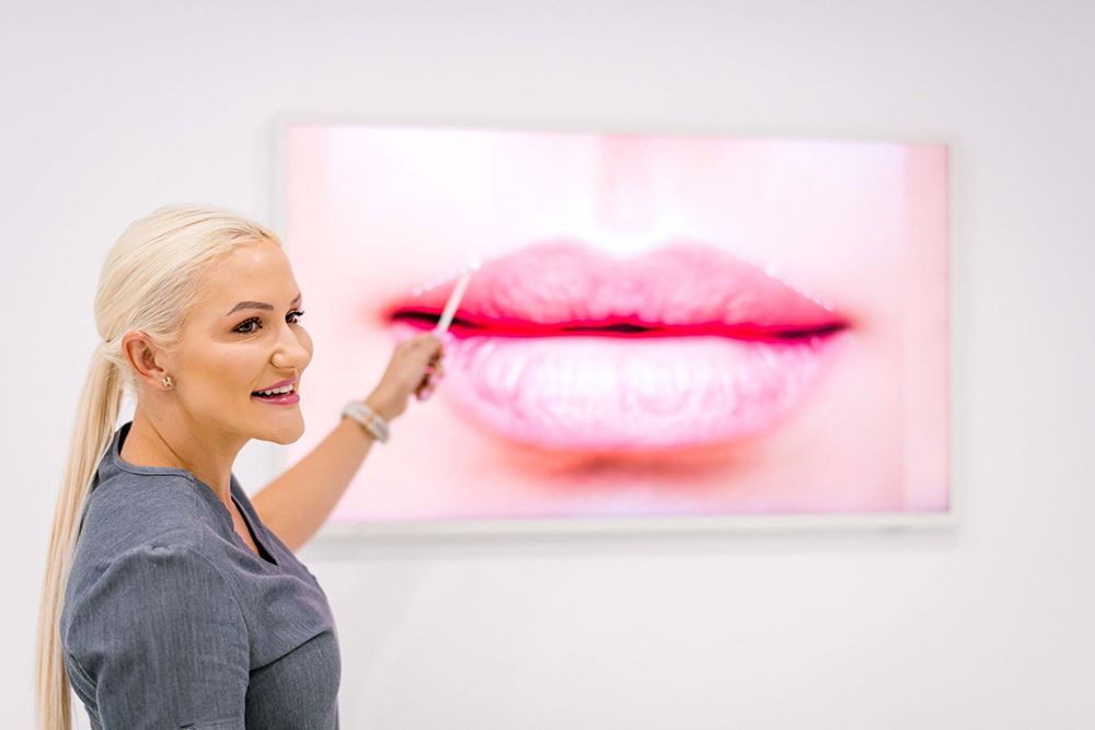 Blonde smiling women pointing the lips on the picture — Cosmetic Procedures in Broadbeach Waters, QLD