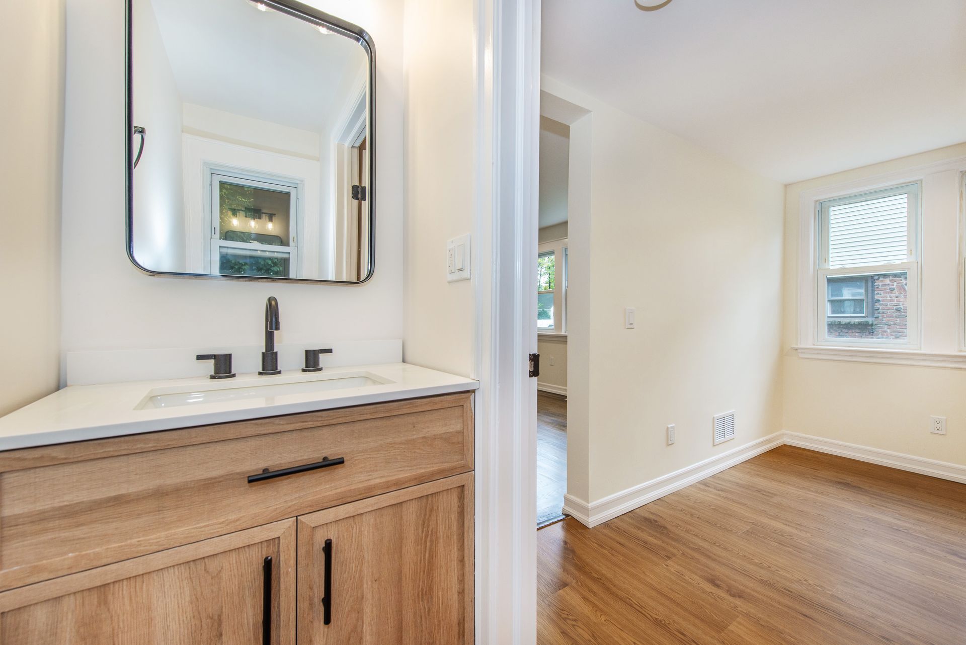 A bathroom with a sink , mirror and wooden cabinets.
