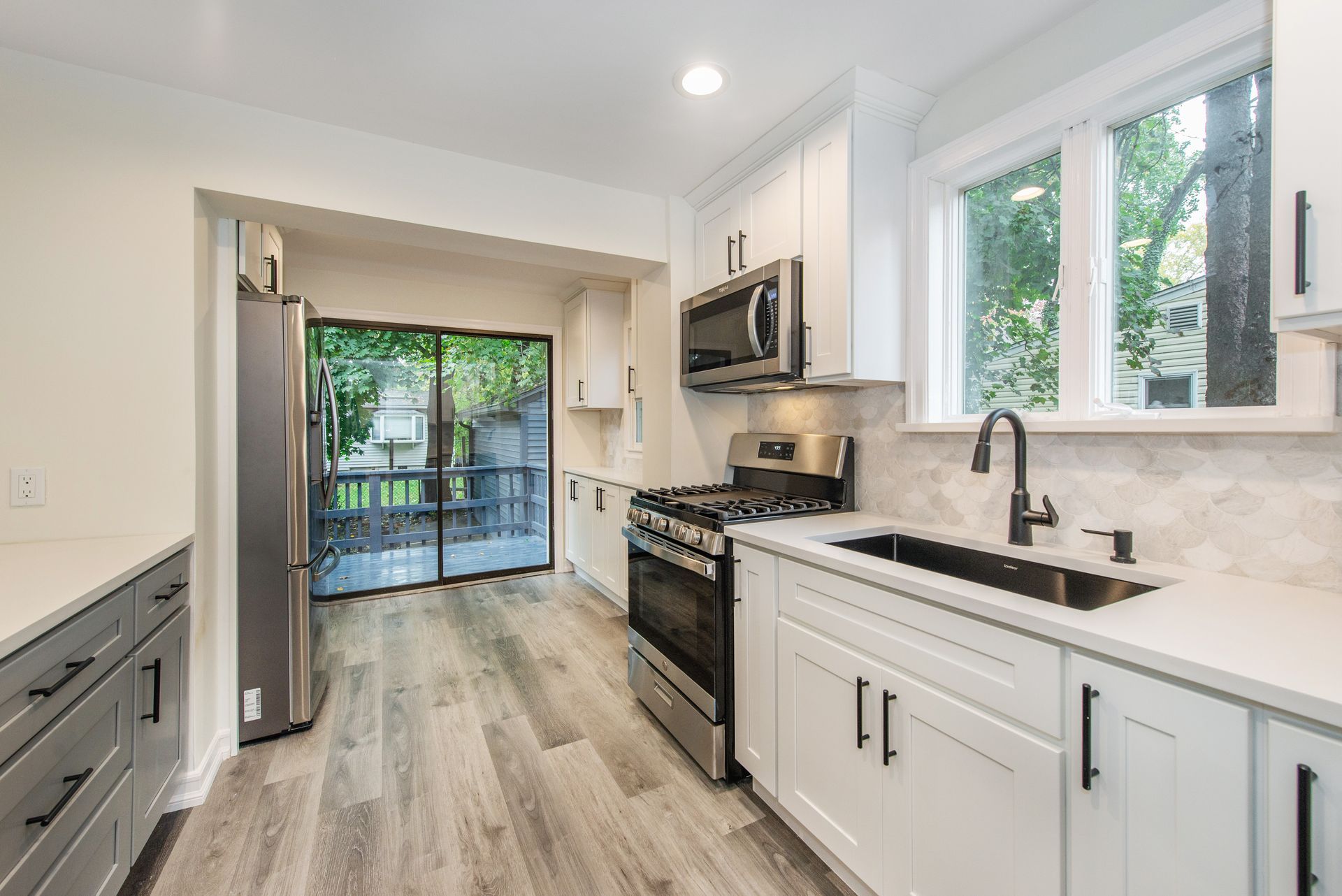 A kitchen with white cabinets , stainless steel appliances , a sink and a stove.