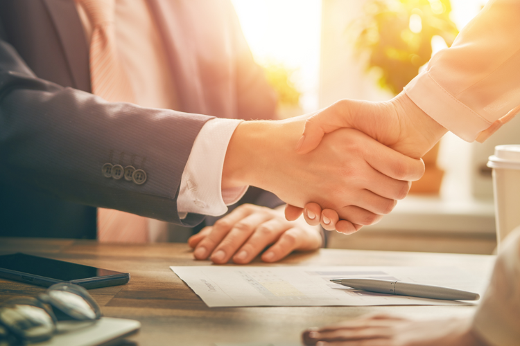 A man and a woman are shaking hands over a table.