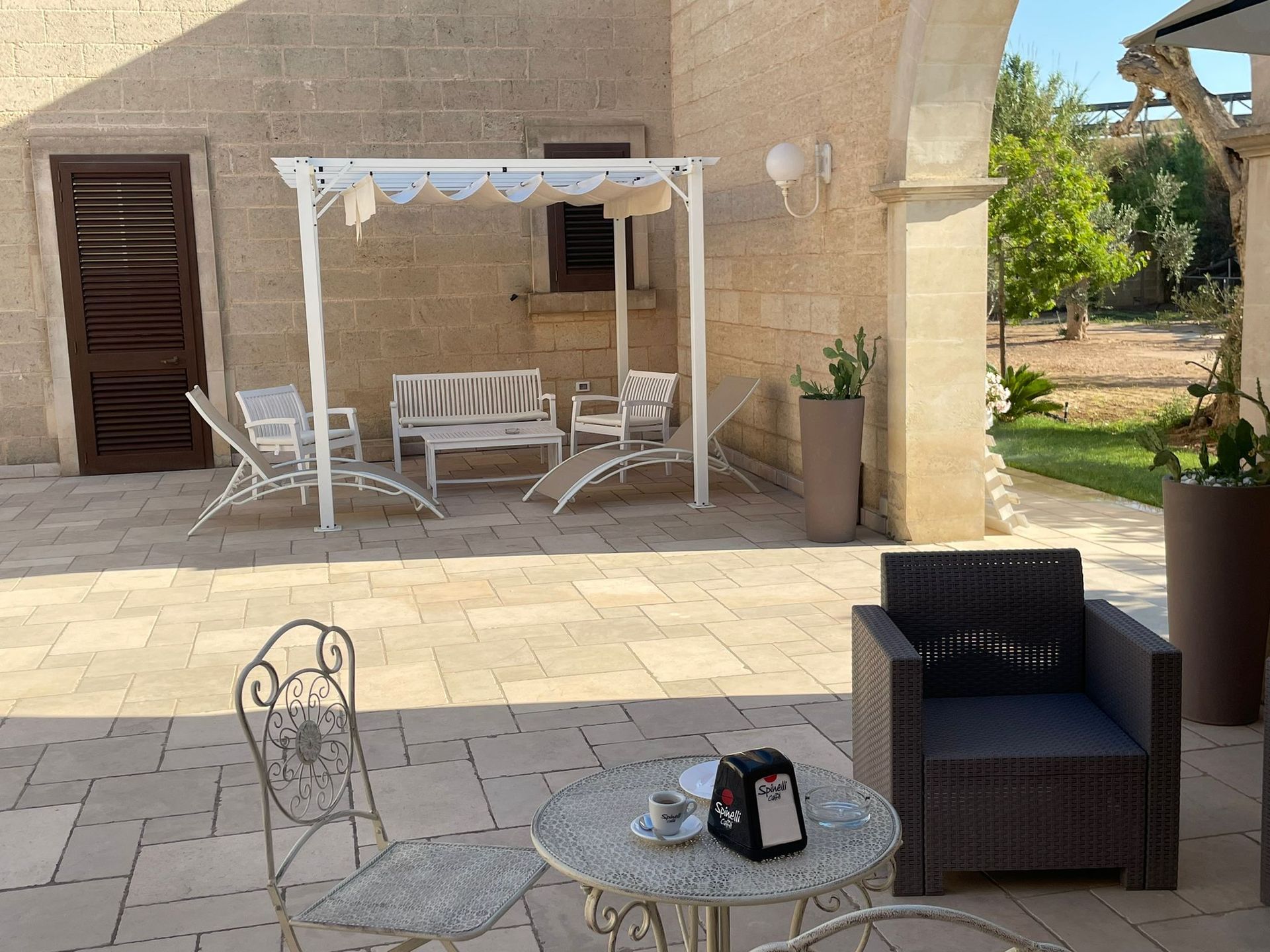 Cortile con posti a sedere: tavolo/sedia in metallo, poltrona imbottita, sedie a sdraio bianche