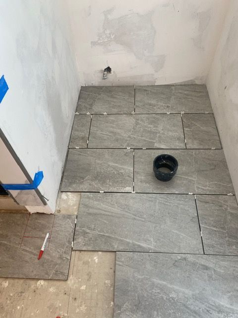 A bathroom floor is being tiled and a bowl of water is on the floor.