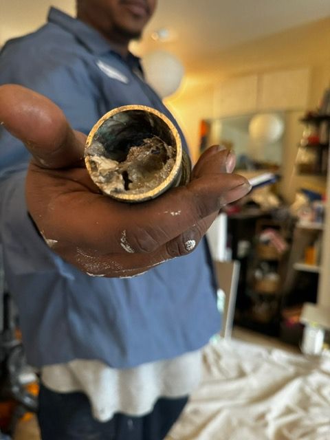 A man is holding a dirty pipe in his hand.