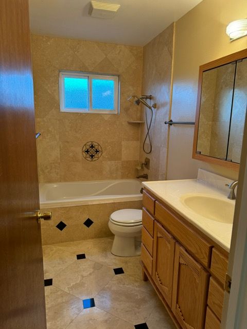 A bathroom with a toilet , sink , tub and mirror