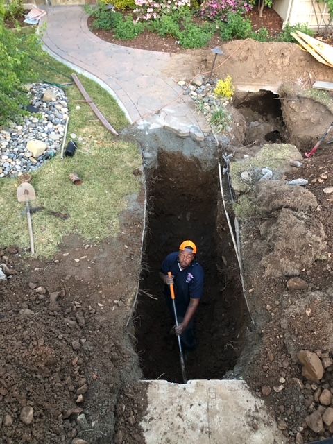A man is digging a hole in the ground with a shovel