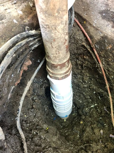 A pipe is sticking out of the ground in a hole.