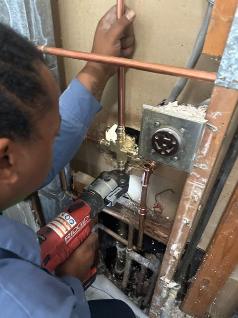 A man is working on a pipe with a drill.