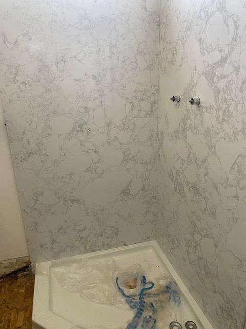 A bathroom with a shower stall and marble walls.