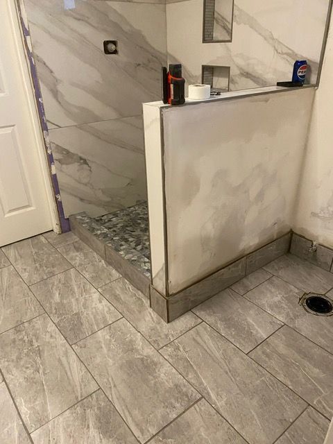A bathroom with a walk in shower and a tiled floor.