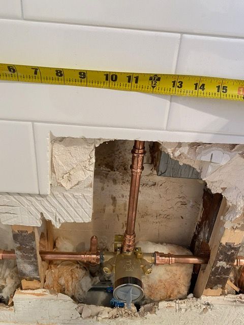 A yellow tape measure is measuring a hole in a wall.