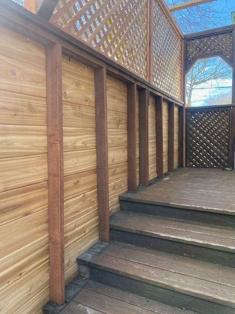 A wooden deck with stairs and a wooden fence.