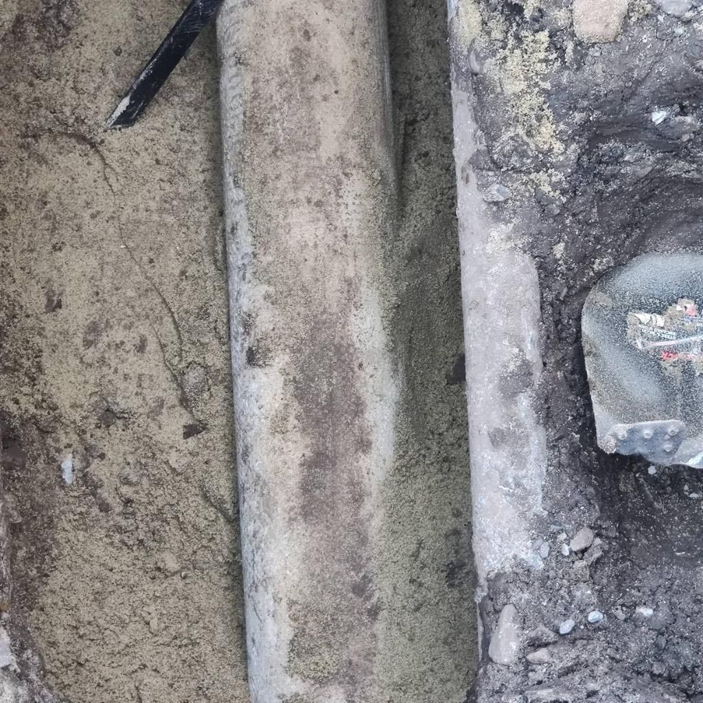 A close up of a metal pipe sitting on top of a pile of dirt.