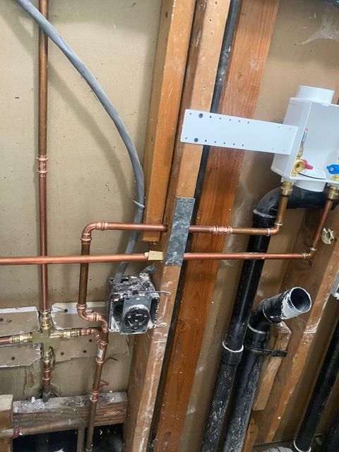 A bunch of pipes are connected to a wall in a bathroom.