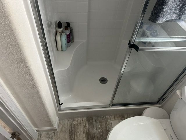 A bathroom with a toilet and a shower stall