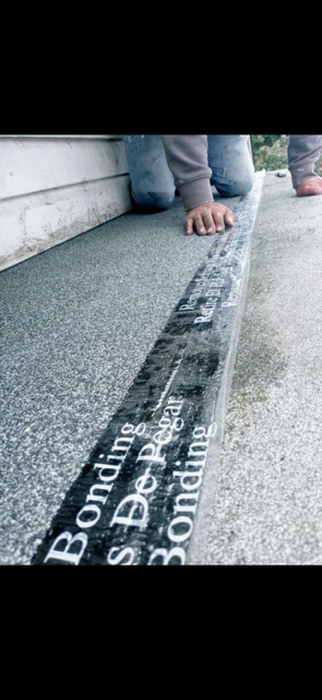 A person is kneeling down on a concrete surface with a black tape that says bonding on it.