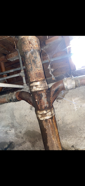 A close up of a rusty pipe in a basement.