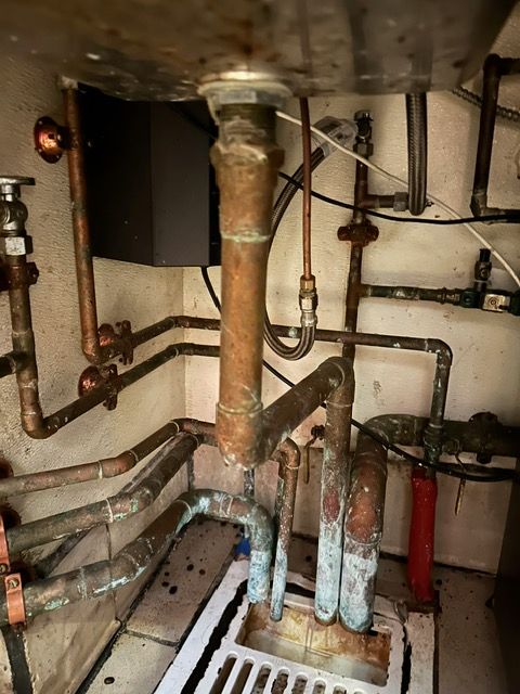 A bathroom sink with a lot of pipes underneath it.