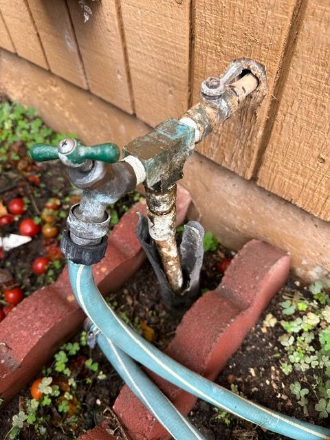 A hose is attached to a faucet on the side of a building.