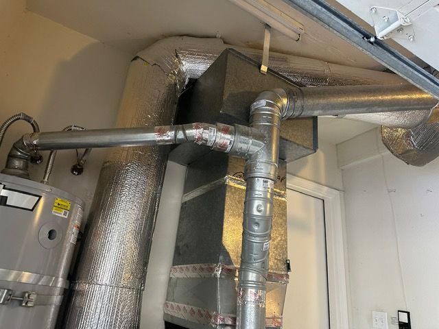 A room with a water heater and pipes coming out of it.