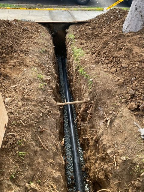 A pipe is being installed in a trench in the ground.