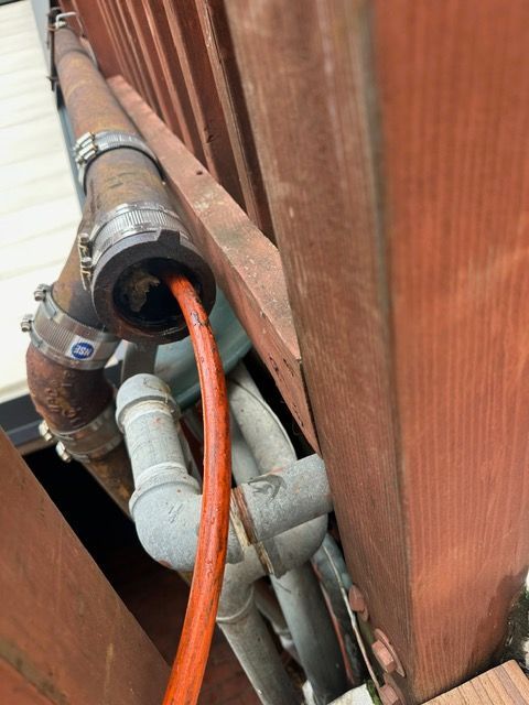 A hose is connected to a pipe on the side of a building.