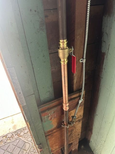A copper pipe is attached to a wooden wall.