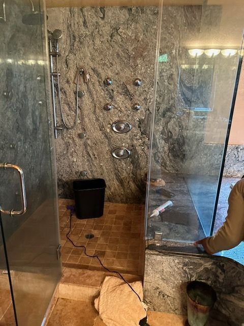 A person is cleaning a shower door in a bathroom.