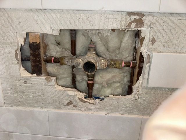 A hole in the wall with pipes coming out of it.