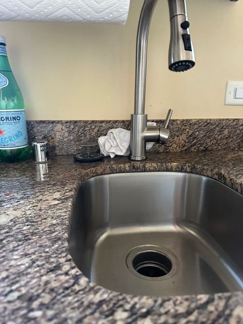 A kitchen sink with a faucet and a bottle of water on the counter.
